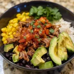 ['Close-up of a vibrant Carnitas Burrito Bowl showcasing layers of ingredients.', 'Side view of a delicious Carnitas Burrito Bowl filled with colorful toppings and textures.', 'Juicy Carnitas Burrito Bowl featuring black beans, corn, salsa, and avocado.', 'Heaping serving of a Carnitas Burrito Bowl with fresh ingredients and a lime wedge.']