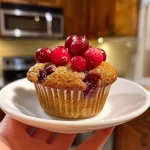['Close-up view of golden-brown Cranberry Orange Protein Muffins with visible fruit pieces.', 'Side angle of freshly baked Cranberry Orange Protein Muffins, highlighting their moist interior and texture.', 'Juicy Cranberry Orange Protein Muffins arranged on a plate, showcasing their vibrant color and crumbly exterior.', 'Mouthwatering close-up of Cranberry Orange Protein Muffins with cranberries and orange zest peeking through.']