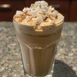 ['Close-up of a frozen vanilla chai latte in a clear glass, topped with whipped cream and a sprinkle of cinnamon.', 'Side view of a refreshing frozen vanilla chai latte, featuring ice cubes and a dollop of whipped cream.', 'Detailed shot of a delicious frozen vanilla chai latte with creamy texture and cinnamon garnish, served in a glass.', 'Elegant presentation of a frozen vanilla chai latte with frosty appearance and optional cream toppings visible.']
