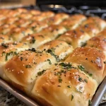['Close-up side view of golden brown garlic herb dinner rolls, showcasing a soft and fluffy texture.', 'Juicy garlic herb dinner rolls arranged on a rustic wooden surface, glistening with melted butter.', 'Freshly baked garlic herb dinner rolls with herbs visible on top, highlighting their delicious appeal.', 'A tempting display of garlic herb dinner rolls with a soft crust, captured in natural light.']
