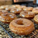 ['Side view of healthy baked apple cider donuts on a wooden table.', 'Close-up shot of golden brown apple cider donuts with a sprinkle of cinnamon.', 'Delicious baked apple cider donuts arranged neatly on a plate.', 'Freshly baked apple cider donuts with a soft texture and cinnamon topping.']