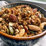 ['Close-up view of a bowl of Healthy Pumpkin Spice Granola with pumpkin seeds and cashews.', 'Side view of Healthy Pumpkin Spice Granola showcasing its crunchy texture and colorful ingredients.', 'Healthy Pumpkin Spice Granola in a bowl, featuring oats, nuts, and spices, captured with an iPhone 15 Pro.', 'Detailed shot of vegan and gluten-free pumpkin spice granola, highlighting pumpkin seeds and almond butter.']