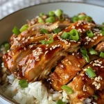 ['Close up of juicy honey garlic chicken thighs served with rice and garnished with scallions and sesame seeds.', 'Side view of boneless skinless chicken thighs glazed in honey garlic sauce with a sprinkle of sesame seeds on top.', 'Delicious slow-cooked chicken thighs in a honey garlic sauce, garnished with chopped scallions and served on a plate.', 'Succulent chicken thighs drizzled with honey garlic sauce, accompanied by rice and topped with green onions and sesame seeds.']