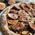 ['A close-up view of a honey-roasted fig and almond galette, showcasing its golden crust and juicy figs.', 'Side perspective of a freshly baked galette filled with roasted figs and almonds, highlighting the flaky texture.', 'An appetizing look at a rustic galette, featuring honey-glazed figs and almond slices on a wooden surface.', 'A detailed view of a fig and almond galette, with glistening honey and sliced almonds on top, presented on a plate.']