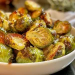 ['Close-up view of roasted Brussels sprouts glistening with maple syrup and Dijon mustard.', 'Side view of crispy golden-brown Brussels sprouts coated in a shiny glaze.', 'Juicy roasted Brussels sprouts marinated in a maple Dijon sauce, displayed attractively.', 'Appetizing side profile of Brussels sprouts with a rich caramelized finish.']