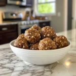 ['Close-up view of No Bake Pumpkin Spice Energy Bites drizzled with chocolate.', 'Side view of several No Bake Pumpkin Spice Energy Bites showcasing their texture.', 'Juicy, round No Bake Pumpkin Spice Energy Bites on a wooden surface.', 'A handful of No Bake Pumpkin Spice Energy Bites with a background of oats and pumpkin.']