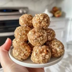 ['Close-up of Peanut Butter Apple Energy Bites, showcasing their textured surface.', 'Side view of a tasty-looking energy bite, highlighting the apple and peanut butter ingredients.', 'Juicy Peanut Butter Apple Energy Bites arranged attractively, with oats and dried apples visible.', 'Detailed view of Peanut Butter Apple Energy Bites, emphasizing their chewy texture and healthy ingredients.']