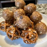 ['Close-up view of Peanut Butter Pretzel Energy Bites with a glossy finish.', 'Side view of stacked Peanut Butter Pretzel Energy Bites showing texture.', 'Delicious Peanut Butter Pretzel Energy Bites with visible pretzel pieces.', 'Healthy snack of Peanut Butter Pretzel Energy Bites arranged on a plate.']