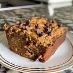 ['Close-up of a slice of moist Protein Pumpkin Bread with chocolate chips.', 'Side view of golden-brown Protein Pumpkin Bread displaying its fluffy texture.', 'A delicious serving of Protein Pumpkin Bread showcasing the dark chocolate chips.', 'Detailed view of Protein Pumpkin Bread with a soft crumb and spices visible.']