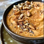 ['Close-up of a vibrant pumpkin chai smoothie bowl topped with sliced banana and pumpkin seeds.', 'Side view of a creamy smoothie bowl featuring pumpkin and chai flavors, adorned with nuts and chia seeds.', 'A delicious smoothie bowl displaying layers of pumpkin puree and topped with granola and cacao nibs.', 'Colorful smoothie bowl made with pumpkin and chai spices, garnished with fresh fruit and seeds.']