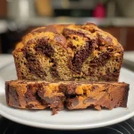 ['A close-up side view of moist pumpkin chocolate swirl bread, showcasing rich chocolate and pumpkin patterns.', 'A slice of pumpkin chocolate swirl bread with a glossy chocolate marble and warm orange pumpkin color.', 'A detailed side view of a loaf of pumpkin chocolate swirl bread, featuring swirls of chocolate throughout the bread.', 'A mouthwatering side profile of pumpkin chocolate swirl bread, highlighting its fluffy texture and chocolate ribbons.']