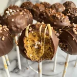 ['Close-up view of delicious Pumpkin Protein Cake Pops with a rich texture and vibrant color.', 'Side view of a plate of juicy Pumpkin Protein Cake Pops, showcasing their smooth surface and appealing design.', 'Detailed shot of Pumpkin Protein Cake Pops, highlighting their creamy coating and decorative chocolate chips.', 'Mouthwatering close-up of a Pumpkin Protein Cake Pop, featuring a mix of flavors and a glossy finish.']