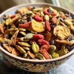 ['Close-up view of colorful Pumpkin Seed Trail Mix with various ingredients.', 'Side view of a bowl filled with Pumpkin Seed Trail Mix featuring plantain chips and goji berries.', 'Detailed image of Pumpkin Seed Trail Mix showcasing raw pistachios, cacao nibs, and pepitas.', 'Vibrant assortment of Pumpkin Seed Trail Mix ingredients with a focus on textures and colors.']