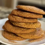 ['Close-up view of golden-brown pumpkin spice sugar cookies on a rustic wooden surface.', 'A side view of freshly baked pumpkin spice sugar cookies with a sprinkle of sugar on top.', 'Juicy pumpkin spice sugar cookies arranged neatly, showcasing their soft texture and warm color.', 'Artistic shot of pumpkin spice sugar cookies, highlighting their inviting aroma and seasonal appeal.']