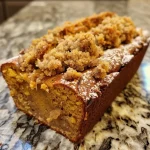 ['Close-up side view of moist Pumpkin Streusel Bread with a glossy browned butter glaze.', 'Detailed view of Pumpkin Streusel Bread showcasing its crumb and topping, with a shiny glaze.', 'Side angle of a slice of Pumpkin Streusel Bread, highlighting the streusel topping and glaze.', 'Close-up image of a slice of Pumpkin Streusel Bread drizzled with brown butter glaze.']