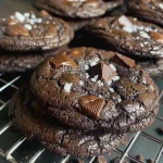 ['Close-up shot of a salted double dark chocolate cookie with glossy chocolate chunks.', 'Side view of a warm, gooey double dark chocolate cookie sprinkled with flaky sea salt.', 'Delicious-looking salted double dark chocolate cookie, showcasing its rich texture and chunks.', 'Juicy double dark chocolate cookie with a golden-brown exterior and melting chocolate pieces.']