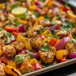 ['Close-up view of juicy honey sriracha chicken on a sheet pan with colorful bell peppers.', 'Side angle of a vibrant sheet pan dish featuring honey sriracha chicken and mixed vegetables.', 'Juicy, glazed chicken pieces with diced red, yellow, and orange bell peppers on a baking sheet.', 'Colorful sheet pan meal showcasing chicken cooked with honey and sriracha, surrounded by fresh veggies.']
