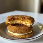 ['Close-up side view of Snickerdoodle Pumpkin Cheesecake Cookies, showcasing their soft texture.', 'A detailed side view of freshly baked Snickerdoodle Pumpkin Cheesecake Cookies with a golden-brown surface.', 'Close-up photo of Snickerdoodle Pumpkin Cheesecake Cookies, emphasizing their creamy filling and spiced exterior.', 'Side view image of pumpkin-flavored Snickerdoodle cookies, highlighting their delicious cheesecake layer.']