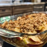 ['Close-up of a homemade apple crisp with golden brown topping and sliced apples visible.', 'Side view of an apple crisp dessert, showcasing layers of apples and crumble topping.', 'Delicious homemade apple crisp presented in a dish, with glistening apples and oats.', 'Detailed view of an apple crisp dessert, highlighting the crunchy topping and juicy apple filling.']