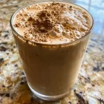 ['Close-up of a creamy vanilla chai protein shake in a glass, with ice cubes visible.', 'Side view of a vanilla chai protein shake topped with a sprinkle of nutmeg, served in a tall glass.', 'Refreshing vanilla chai protein shake with visible chai tea and ice, set against a simple background.', 'A delicious-looking vanilla chai protein shake in a glass, showcasing its creamy texture and spices.']