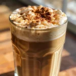 Close-up view of a creamy Cinnamon Brown Sugar Cold Foam Iced Coffee in a clear glass.
