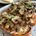 Close-up of a slice of Garlic Mushroom Toast topped with sautéed mushrooms and herbs.