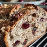 Close-up side view of freshly baked walnut and cranberry sourdough bread with a golden crust.